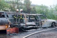 Feuerwehrleute stehen hinter einer ausgebrannten Stretch-Limousine