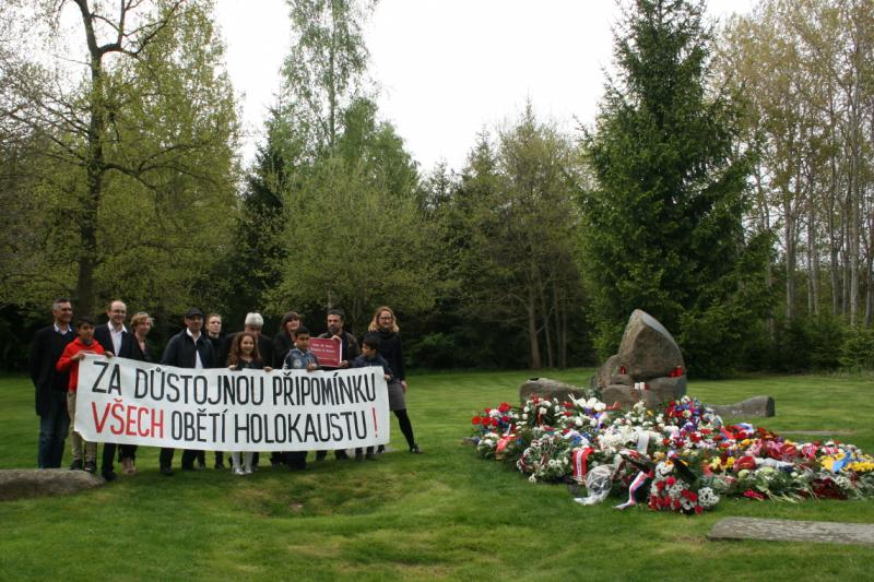 Aktivist_innen mit Banner am Gedenkstein: "Ein würdiges Gedenken für alle Opfer des Holocaust"