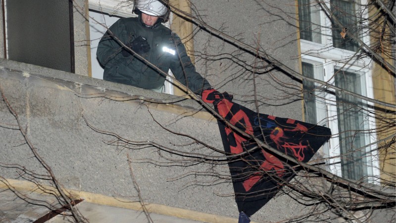 Ein Polizist entfernt auf einem Balkon ein von den Besetzern angebrachtes Transparent