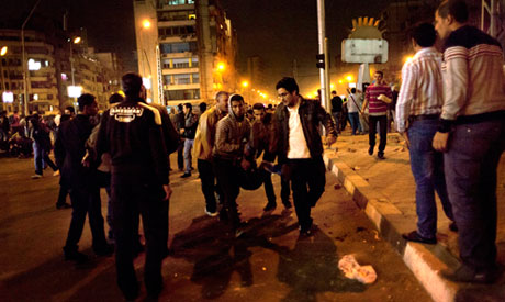 Protesters opposed to Egyptian President Mohamed Morsi evacuate an injured fellow protester during clashes between supporters of Morsi and their rivals in front of the presidential palace in Cairo