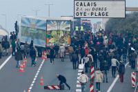 Dozens of migrants gather near lorries which head towards the ferry terminal in Calais