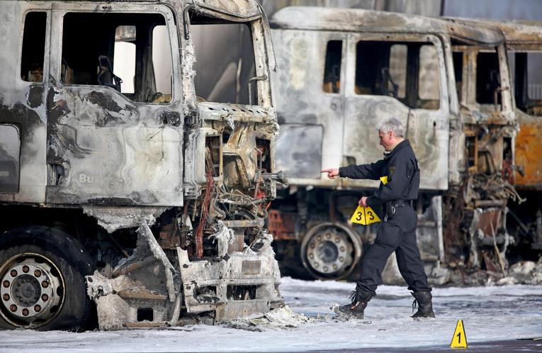 Ein Polizist sichert Spuren an mehreren ausgebrannten Lkw der Bundeswehr am Dienstag in Leipzig. Unbekannte Brandstifter haben auf dem Werkstattgelände acht Lastwagen und zwei Anhänger angezündet - sechs dieser Fahrzeuge gehören der Bundeswehr.